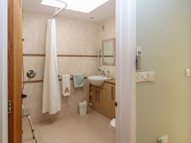 A bathroom with a shower curtain a sink with cabinet and towels at Badger's Den in Budleigh Salterton