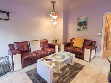 A living room with two leather sofas a glass coffee table and a hanging light at 1 The Old Coach House in Ambleside