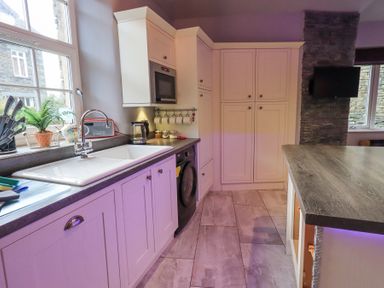A kitchen with white cabinets a sink a microwave and a washing machine at 1 The Old Coach House in Ambleside