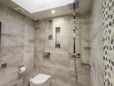 A bathroom with a toilet paper holder and wall-mounted toilet at The Old Coach House in Ambleside