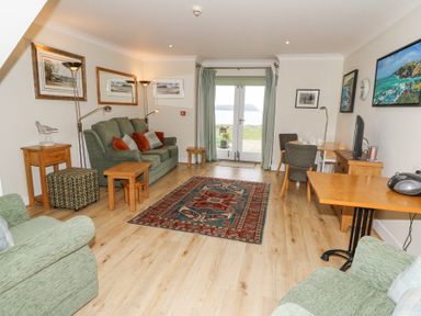A living room with sofas tables and paintings on the walls at Carningli Suite near Newport