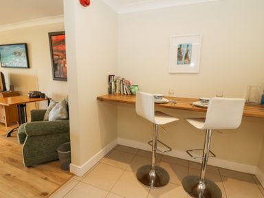 A kitchen counter with two white bar stools and place settings at Carningli Suite near Newport