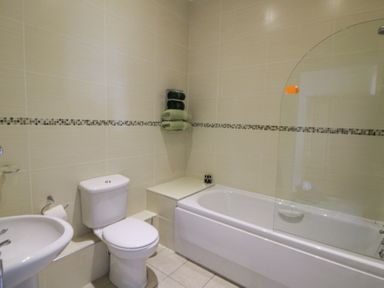 A bathroom with a toilet sink bathtub and towels on wall at Carningli Suite near Newport