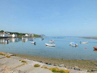 A coastal scene with boats on calm water and houses along the shore at Carningli Suite near Newport