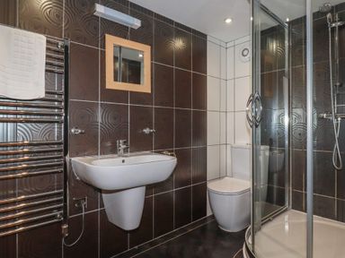 A bathroom with a pedestal sink toilet glass shower enclosure and heated towel rail at St Georges in Padstow