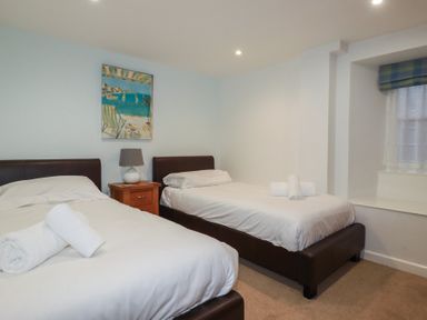 A bedroom with two single beds a nightstand with lamp and a framed painting at St Georges in Padstow