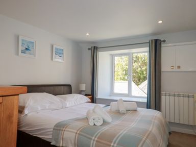 A bedroom with a bed with rolled towels and framed pictures on the wall at St Saviours in Padstow