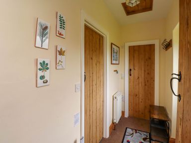A hallway with wooden doors framed artwork a small bench a radiator and a rug at Folly View in Eglingham