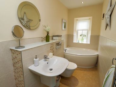 A bathroom with a sink toilet bathtub window and decorative items at Folly View in Eglingham