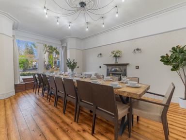 A dining room with a large wooden table and chairs set for a meal with plates glasses and bowls at Fir Trees in Windermere