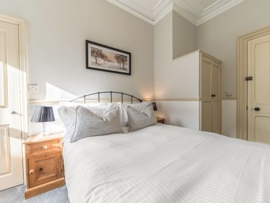 A bedroom with a double bed two bedside tables with lamps a framed picture and a built in wardrobe at Fir Trees in Windermere