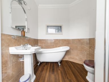 A bathroom with a pedestal sink a clawfoot bathtub a toilet and a framed picture on the wall at Fir Trees in Windermere