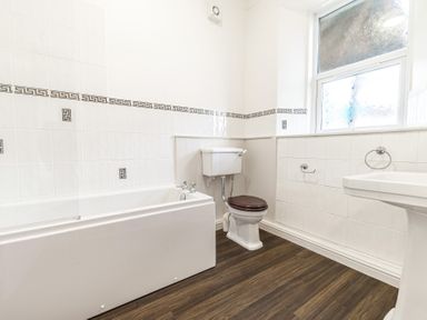 A bathroom with a bathtub toilet and sink and a window at Fir Trees in Windermere