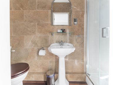A bathroom with a pedestal sink a mirror and a shower enclosure at Fir Trees in Windermere