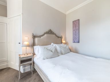 A bedroom with a double bed two bedside tables with lamps and a decorative panel on the wall at Fir Trees in Windermere