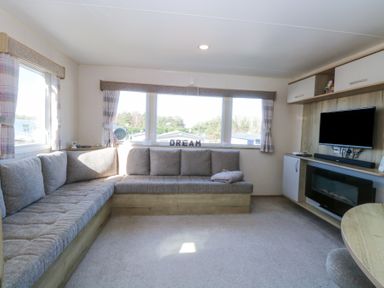 A living room with a corner sofa a television and a fireplace at 31A Foxburrow Hang Fritton near Belton Norfolk
