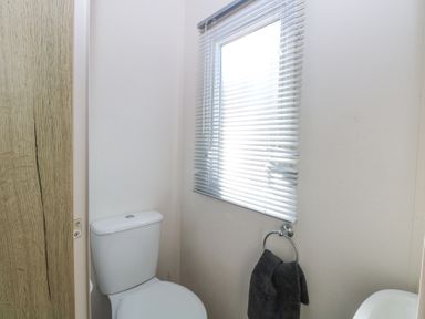 A bathroom with a toilet a window with blinds and a towel hanging on a ring at 31A Foxburrow Hang in Fritton near Belton Norfolk