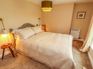 A bedroom with a bed a side table and lamps at Kirkland Howe Cottage in Arlecdon