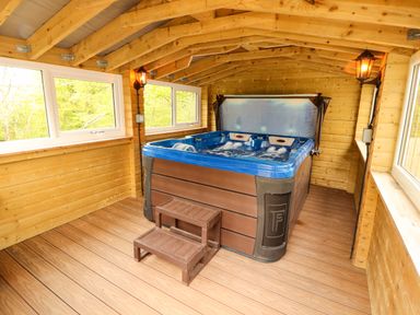 A wooden cabin interior with a hot tub and two steps at Kirkland Howe Cottage in Arlecdon