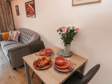 A dining table with croissants and tableware near a sofa with cushions and wall art at Duchess of Hamilton @ Engine Shed in Whitby