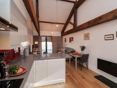 A kitchen and living area with wooden beams and a small dining table at Duchess of Hamilton @ Engine Shed Whitby