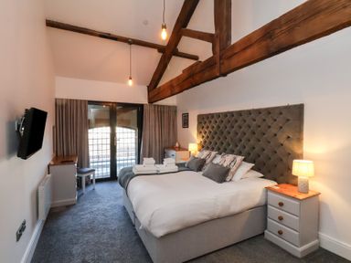 A bedroom with a large bed side tables lamps curtains and wooden beams at Duchess of Hamilton @ Engine Shed in Whitby
