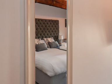 A bedroom with a tufted headboard, a bed with pillows and folded towels reflected in a mirror at Duchess of Hamilton @ Engine Shed in Whitby