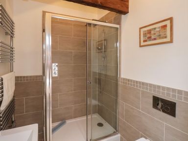 A bathroom with a glass shower enclosure tiled walls a towel rack and a framed picture on the wall at Duchess of Hamilton @ Engine Shed in Whitby
