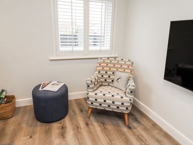 A living room with an armchair and ottoman at North Sands in Beadnell
