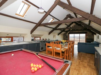 A kitchen dining and living area with a pool table wooden dining table and blue sofas at Llwyngwinau Isaf Barn in Tynreithyn near Tregaron
