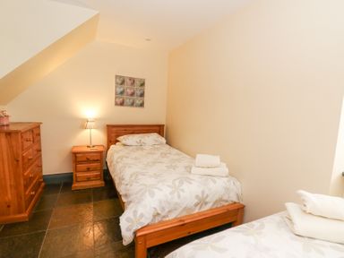 A bedroom with two single beds a wooden dresser and bedside table with a lamp at Llwyngwinau Isaf Barn in Tynreithyn near Tregaron