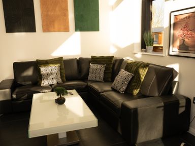 A corner seating area with a black leather sofa and a white coffee table at The Green Monkey in North Hykeham