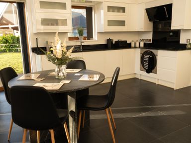 A kitchen with a round dining table and black chairs with flowers on the table at The Green Monkey in North Hykeham