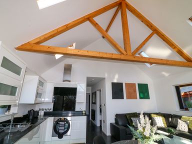 A kitchen and living area with wooden ceiling beams and a black leather sofa at The Green Monkey in North Hykeham