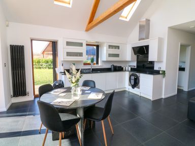 A kitchen with white cabinets a black round dining table with four chairs and skylights at The Green Monkey in North Hykeham