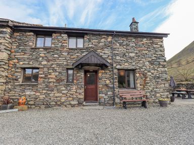 Stone cottage exterior with wooden door windows bench and outdoor seating at Low Wood View in Hartsop