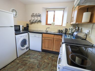 A kitchen with a refrigerator washing machine dishwasher stove and cupboards at Low Wood View in Hartsop