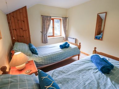 A bedroom with two single beds blue bedding and rolled towels on the beds at Low Wood View in Hartsop