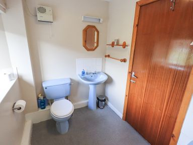 A bathroom with a toilet sink mirror wooden door and shelves at Low Wood View in Hartsop