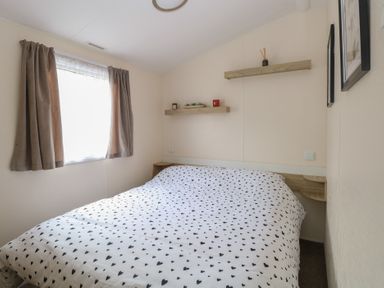A bedroom with a bed covered in a heart patterned duvet and shelves above at 31B Foxburrow Hang in Fritton near Belton Norfolk