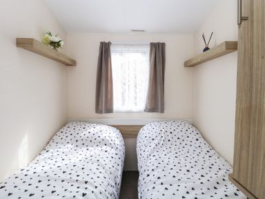 A bedroom with two single beds with heart-patterned bedding and two shelves with decorative items at 31B Foxburrow Hang in Fritton near Belton Norfolk