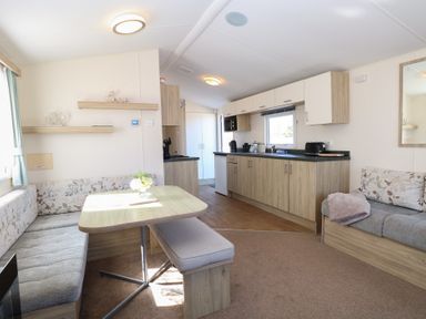 A kitchen and dining area with wooden cabinets and a table with a bench and upholstered seating at 31B Foxburrow Hang in Fritton near Belton Norfolk