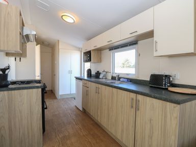 A kitchen with wooden floor and cabinets a window black toaster and microwave oven at 31B Foxburrow Hang in Fritton near Belton Norfolk