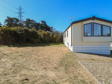 A mobile home with gravel area and bushes under clear sky at 31B Foxburrow Hang in Fritton near Belton Norfolk