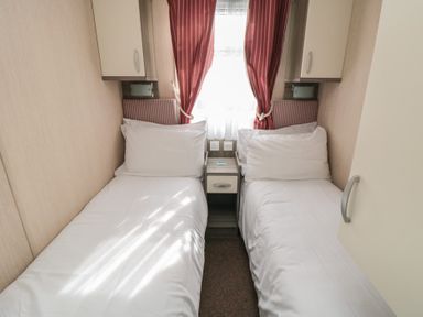 A small bedroom with two single beds and a nightstand between at Rose Bank D8 in Primrose Valley