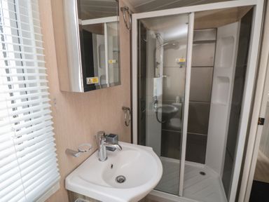 A bathroom with a sink, mirror cabinet, and a glass-enclosed shower at Rose Bank D8 in Primrose Valley