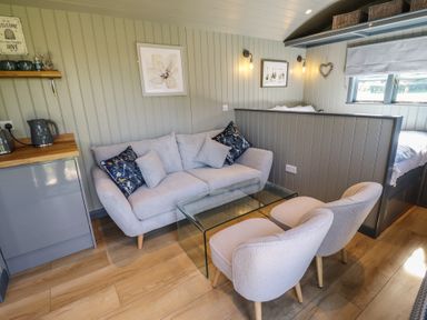 A small seating area with a sofa, two chairs, and a glass coffee table in a room at Buttercup in Ashby-cum-Fenby near Waltham