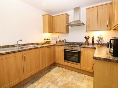 A kitchen with wooden cabinets a stainless steel oven a sink and a countertop at The Baler House in Hayle