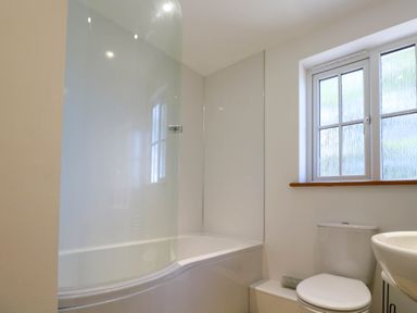 A bathroom with a bathtub shower combination a toilet and a sink at The Baler House in Hayle