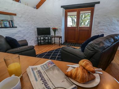 A living room with croissants on a table and a television at Bay View Barn in Hayle